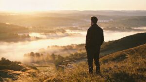 Personne seule sur une colline au lever du soleil dans une atmosphère paisible.